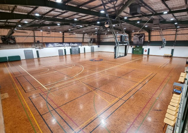 A photo taken from the inside seating area of Bolton Park Stadium showing the two courts set up for basketball.