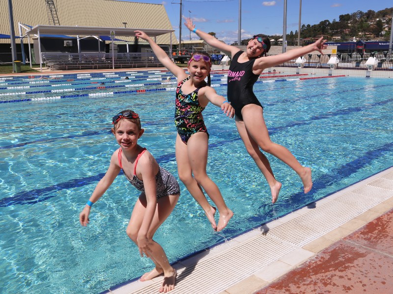 Three children jumping into the pool